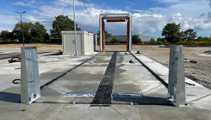 Centre de lavage automatique ID WASH avec portique pour poids lourd à l'arrêt et buses de lavage de châssis en entrée de piste